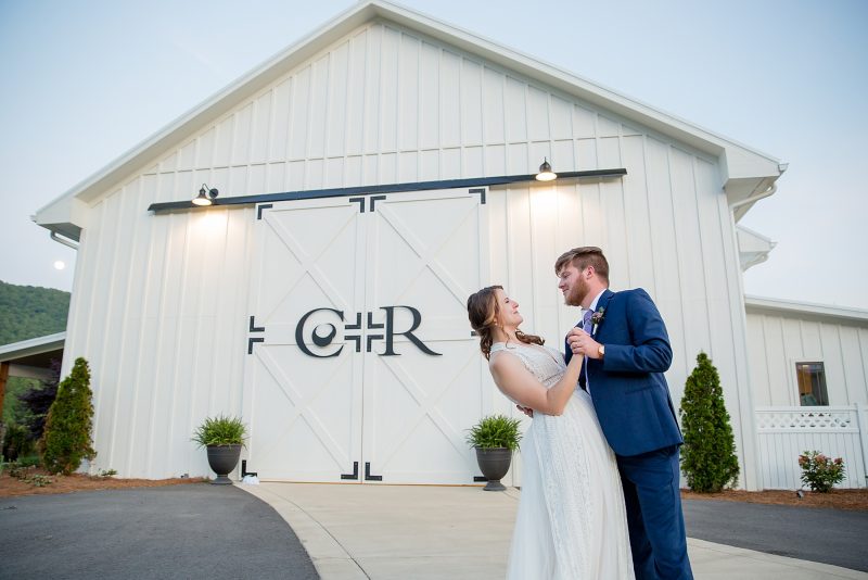 Bride and groom pose in front of Chestnut Ridge main ceremony and reception space in Canton NC
